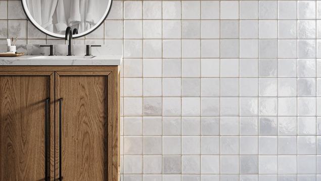 Bathroom with white tile backsplash, beige grout, and vanity with wood base and white marble top.